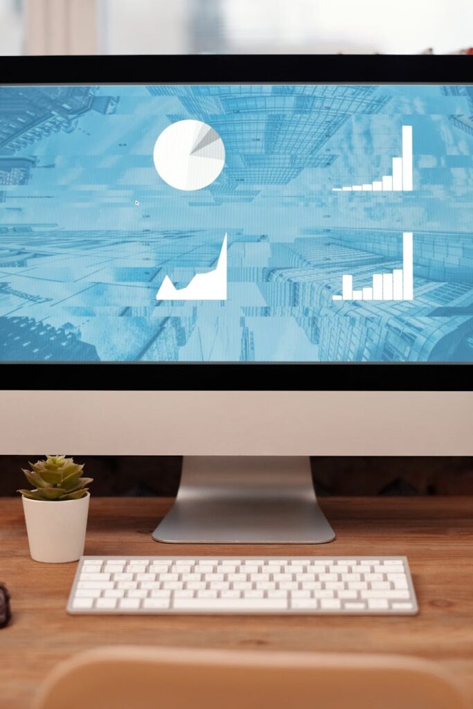 Stylish home office setup with desktop, plant, and eyeglasses on a wooden desk.