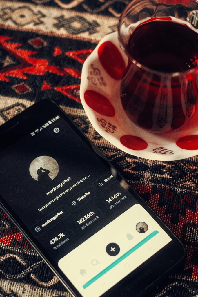Overhead view of a vintage cup of tea next to a smartphone on a patterned surface, creating a cozy atmosphere.