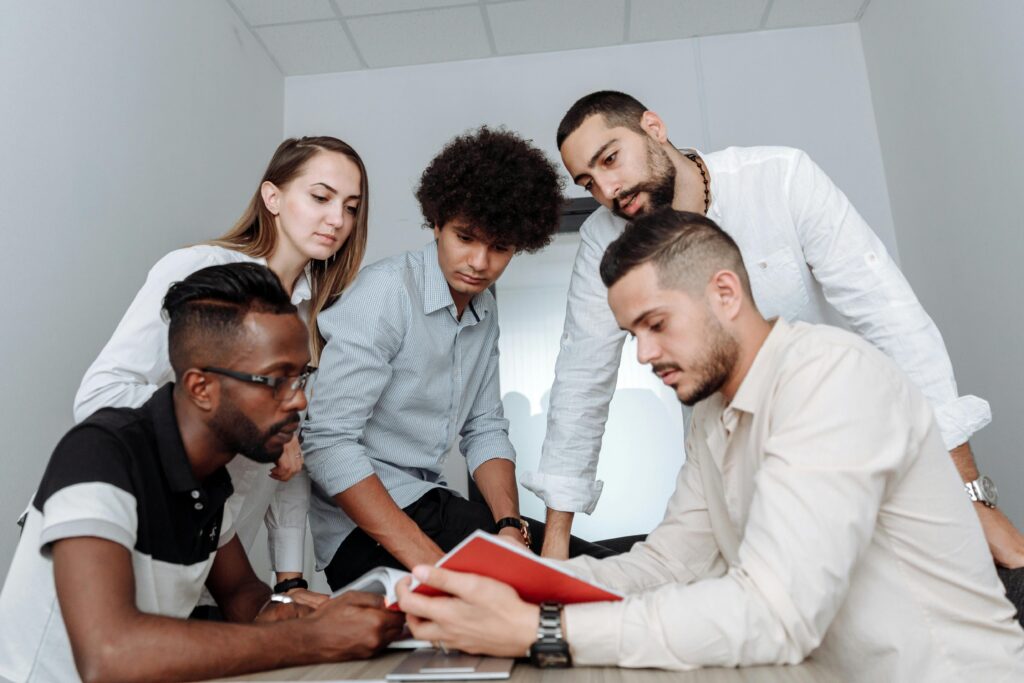A multicultural team engaged in a collaborative office meeting, discussing ideas around a table.