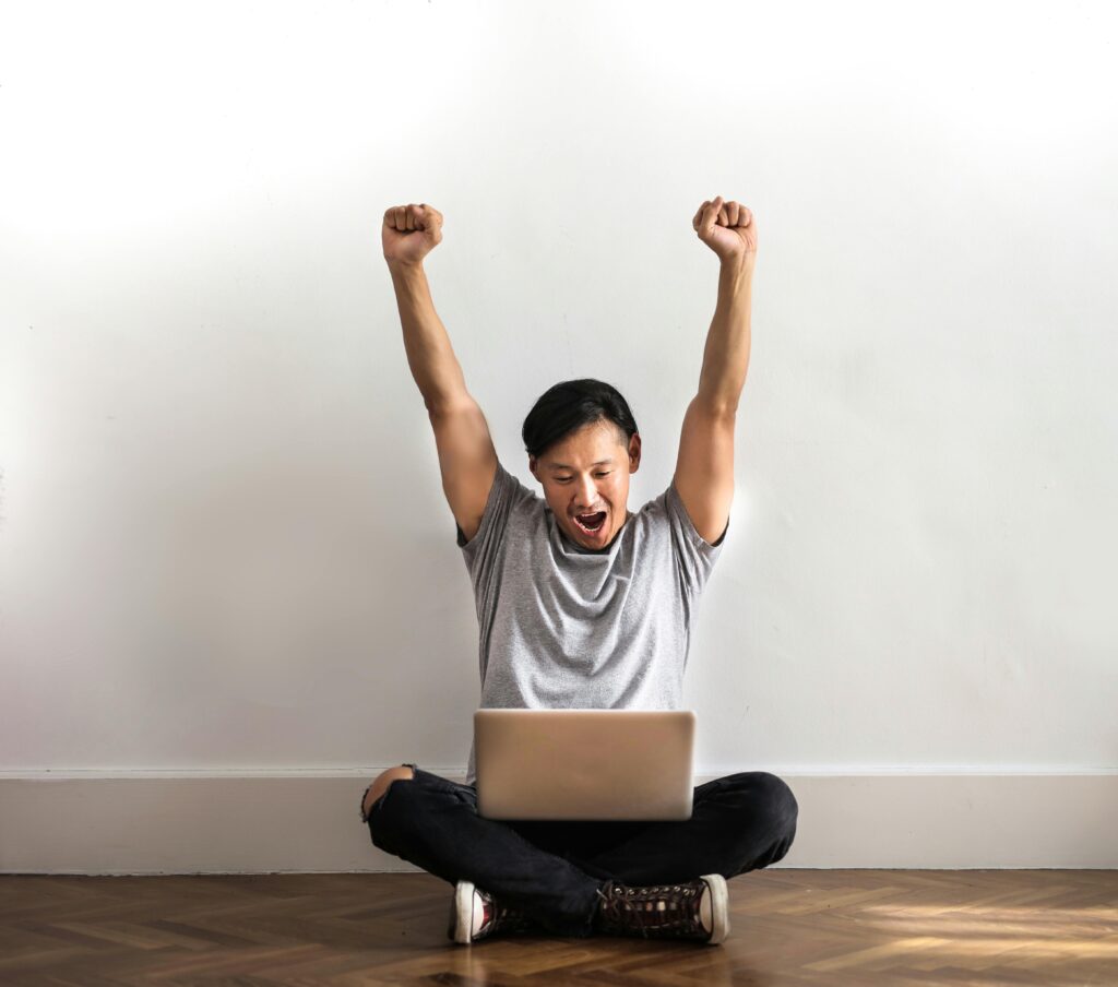 pexels-photo-3760609-3760609 Young man joyfully celebrating success with a laptop indoors.